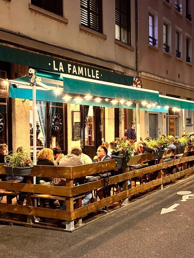 La façade et la terrasse de La Famille, le soir, guirlandes allumées