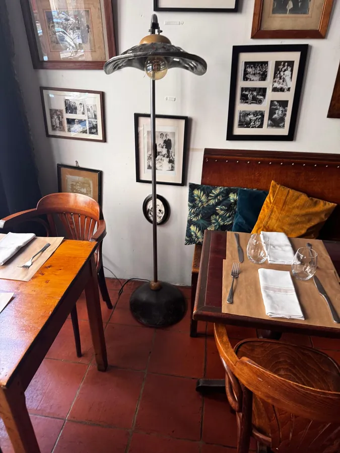 Un coin de salle, tables dressées sous le mur de cadres
