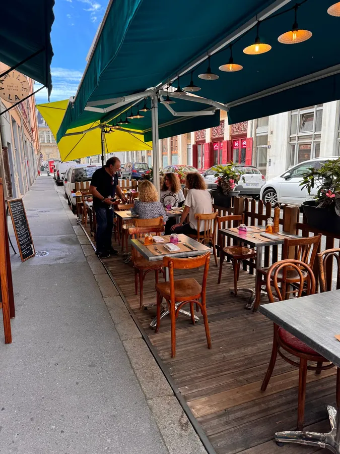 La terrasse de La Famille en été, sous les stores verts, rue Duviard